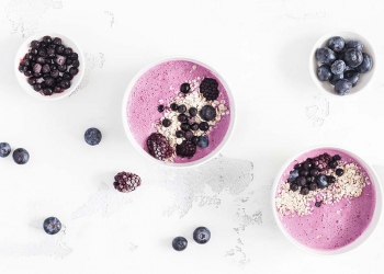 Breakfast with muesli, acai blueberry smoothie, fruits on white background. Healthy food concept. Flat lay, top view