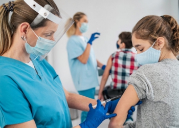 Doctor vaccinating girl. Injecting COVID-19 vaccine into patient's arm