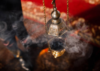 A priest's censer hangs on an old wall in the Orthodox Church. Copper incense with burning coal inside. Service in the concept of the Orthodox Church. Adoration.