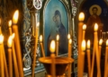 Blurred wax burning candles in an orthodox church on the icon background.